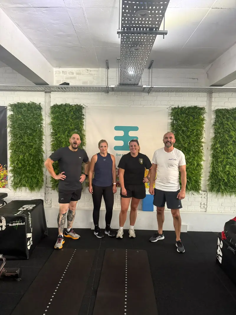 Four members together in front of the be:unique logo wall