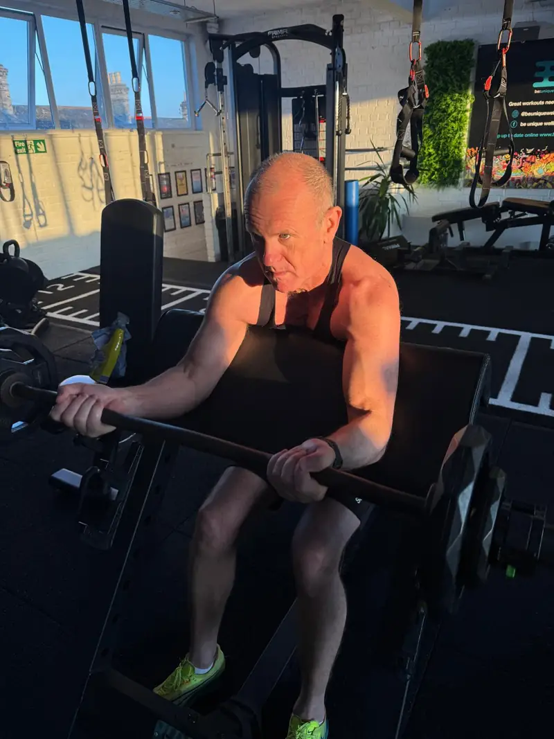 An older member doing a preacher curl in the morning light