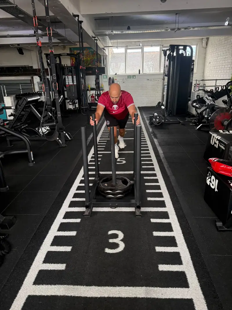 A member pushing the sled down the numbered turf track
